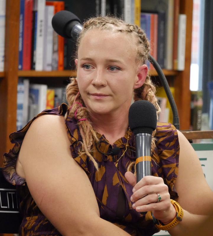 Reality Winner holding a microphone while speaking at a bookstore event in 2025